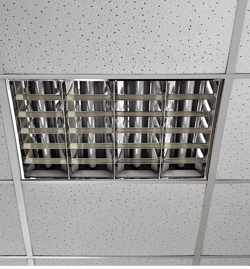 Fluorescent light fixture on tiled ceiling.